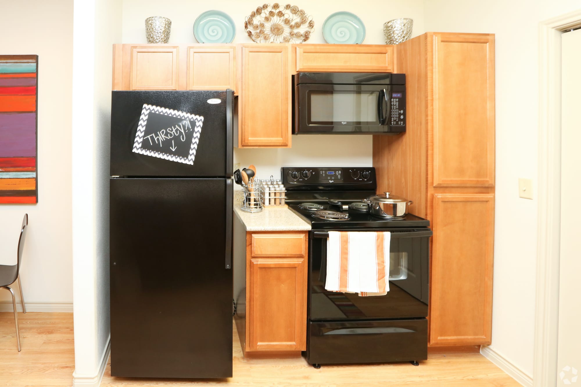 Black appliances in a kitchen with a sign that says, "Thirsty?"