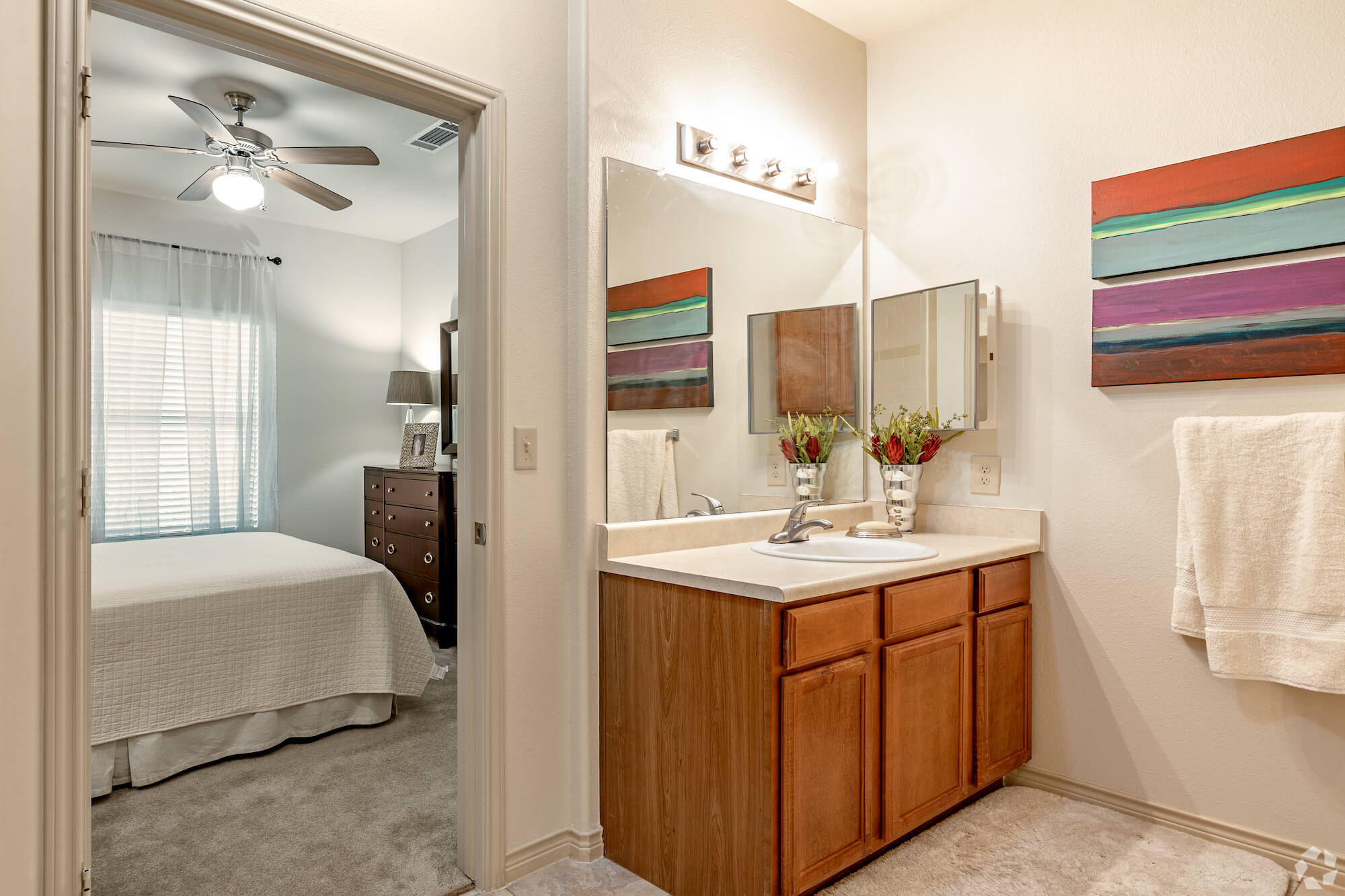 A brightly-lit bathroom looking into the bedroom.