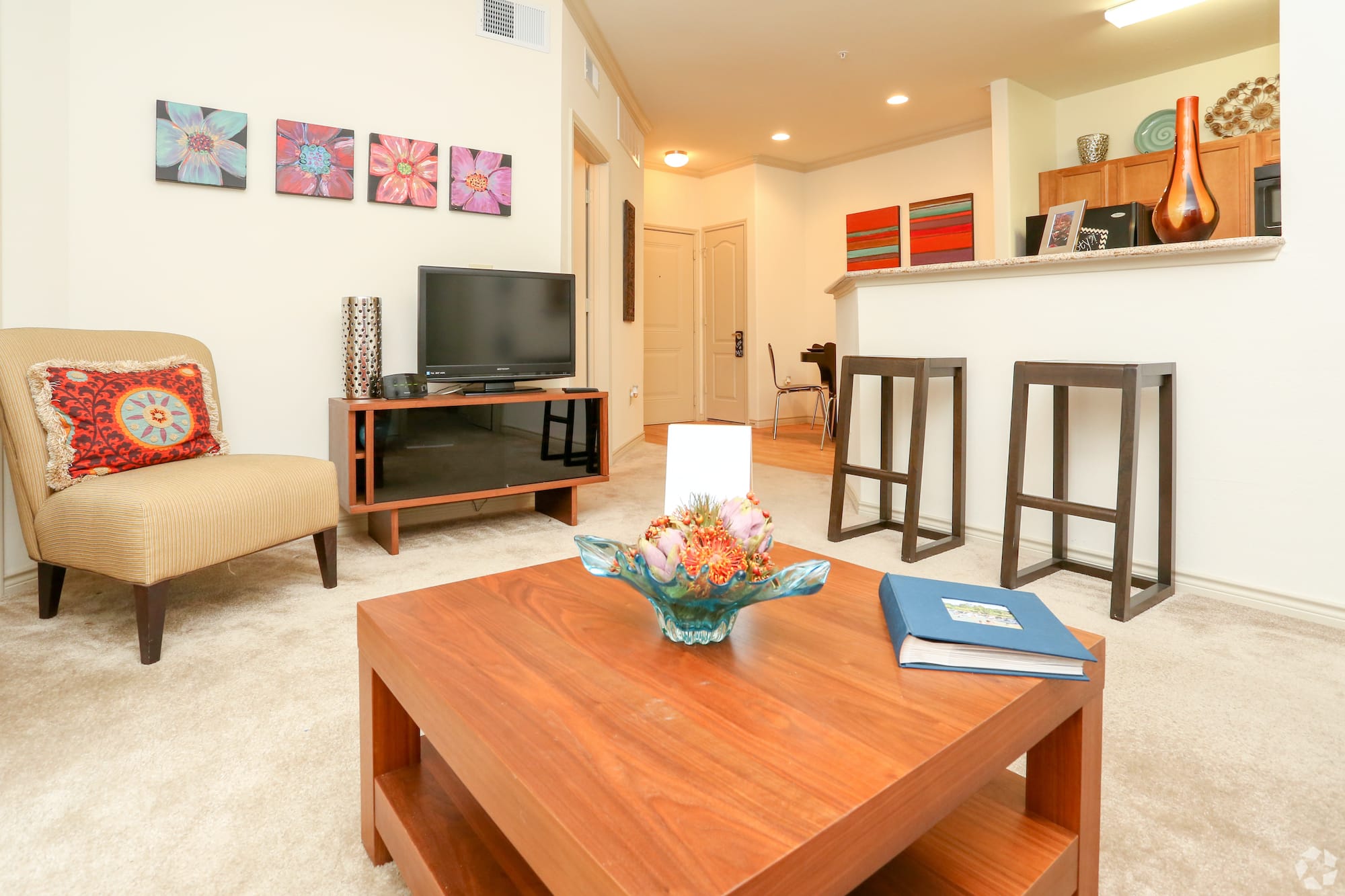 View from the couch to the entrance of the apartment showing a full entertainment center along the opposite wall.